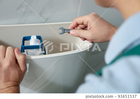 Professional plumber repairing toilet in bathroom, closeup 91651537