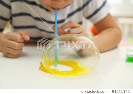 Little boy blowing slime bubble on white table, closeup Little boy blowing slime bubble on white table, closeup 91651543
