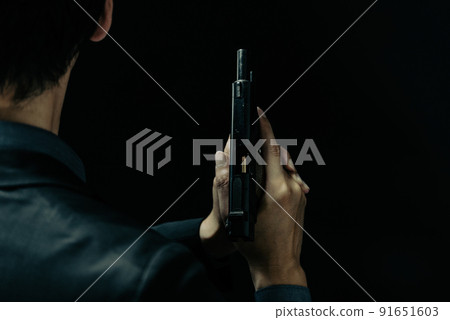 A person in a suit holding a pistol 91651603