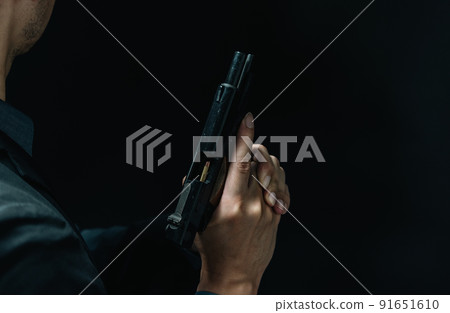 A person in a suit holding a pistol 91651610