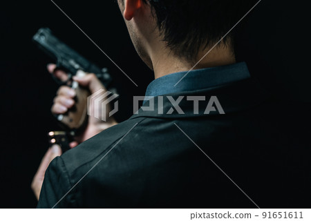 A person in a suit holding a pistol 91651611