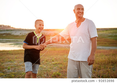 Son and dad standing against the backdrop of a colorful 91651698