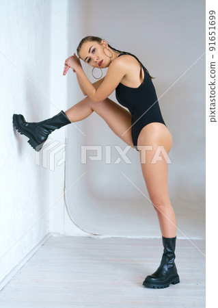 Beautiful young woman in a black bodysuit and boots posing Beautiful young woman in a black bodysuit and boots posing 91651699