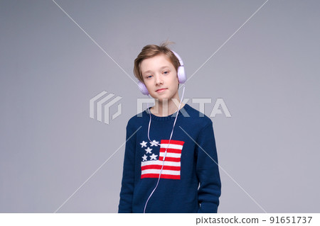 Happy caucasian boy wearing wired headphones listening to music with contented 91651737
