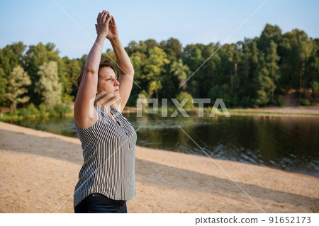 Mature woman at holiday destination beach contemplating lake sitting on shore 91652173