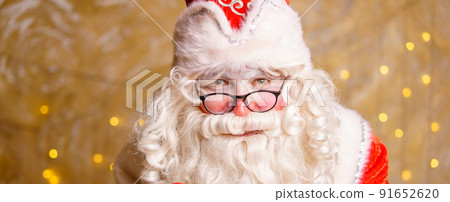 Portrait of santa claus in glasses looking at camera against background Portrait of santa claus in glasses looking at camera against background 91652620