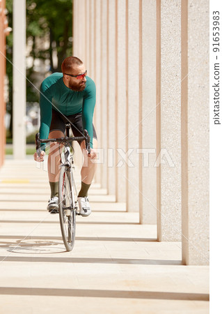 Caucasian handsome young man in protective helmet goes out for bicycle ride through city streets on blurred background. Cyclist male ride bike outdoors in urban. Caucasian handsome young man in protective helmet goes out for bicycle ride through city streets on blurred background. Cyclist male ride bike outdoors in urban. 91653983