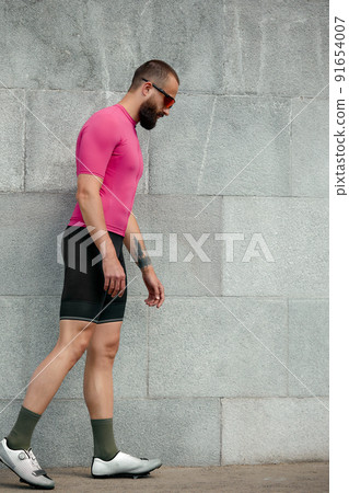 Tired sportsman in pink sportwear resting after an workout while standing against cement wall background with copy space area for text message or advertising, man runner taking break after run Tired sportsman in pink sportwear resting after an workout while standing against cement wall background with copy space area for text message or advertising, man runner taking break after run 91654007