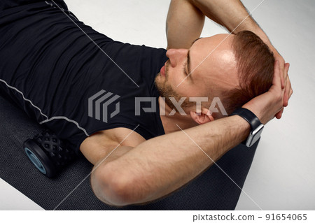 Man foam rolling. Athlete stretches using foam roller. Man foam rolling. Athlete stretches using foam roller. 91654065
