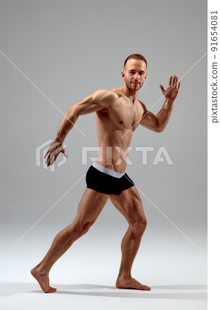 Young male athlete posing. Handsome athletic male power guy. Fitness muscular person. Young athlete showing muscles in the studio, posing shirtless on gray background. 91654081