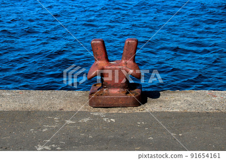 Old Red Painted Bollard at a Coastal Harbour Location 91654161