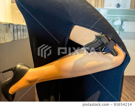 a woman in an evening black dress holds a pistol in stockings. black, small, compact pistol. military weapon. special agent on a mission a woman in an evening black dress holds a pistol in stockings. black, small, compact pistol. military weapon. special agent on a mission 91654214