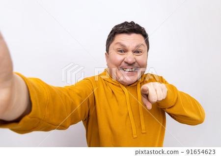 Portrait of delighted man blogger pointing at you, looking at camera with toothy smile, POV, point of view of photo, wearing urban style hoodie. Indoor studio shot isolated on white background. Portrait of delighted man blogger pointing at you, looking at camera with toothy smile, POV, point of view of photo, wearing urban style hoodie. Indoor studio shot isolated on white background. 91654623