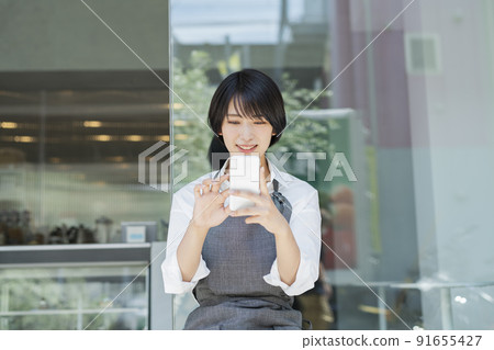 使用咖啡館智能手機的女性職員 91655427
