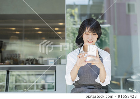 Female staff using a cafe smartphone 91655428
