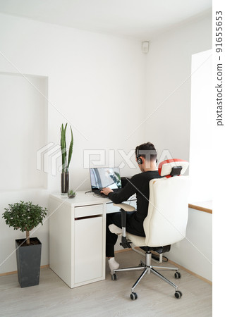 Guy in headphones working on laptop in light interior Guy in headphones working on laptop in light interior 91655653