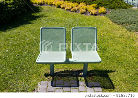 Steel park bench. View of a modern green bench in the park, summer time 91655716