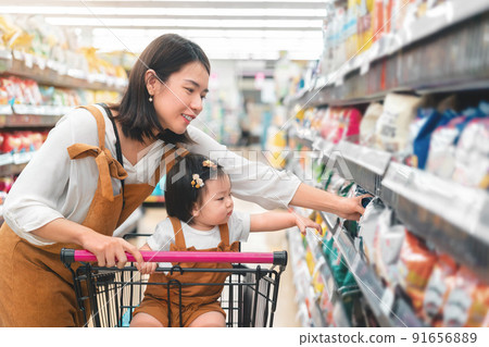 Asian mother and her daughter buying food at huge supermarket , Baby sit in trolley, Family shopping concept. 91656889