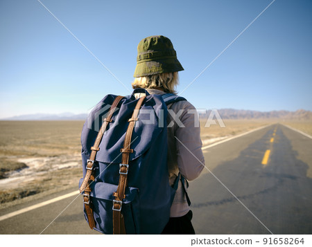 rear view of asian woman female backpacker walking on empty highway 91658264