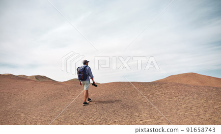 asian male backpacker landscape photographer walking on a hill looking at view, rear view 91658743
