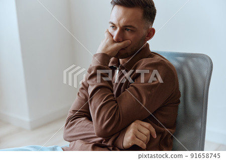 Upset frustrated thoughtful pensive serious young man reclines on hand looks aside think about divorce break up sitting in chair at home. People emotions Problems concept. Copy space 91658745