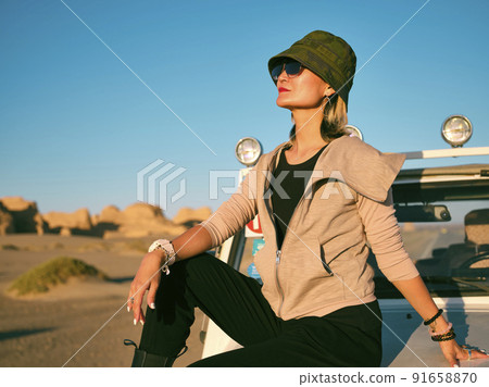 fashionable asian woman sitting on the hood of a car in national geological park fashionable asian woman sitting on the hood of a car in national geological park 91658870