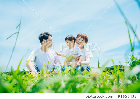 Parents and children sitting on a sunny green space 91659435