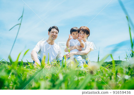 Parents and children sitting on a sunny green space 91659436