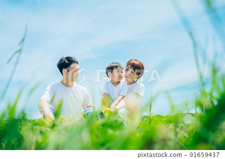 Parents and children sitting on a sunny green space Parents and children sitting on a sunny green space 91659437