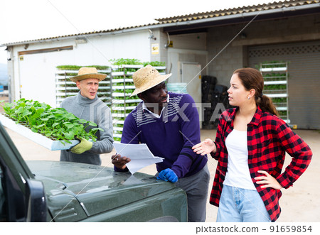 Female farmer discussing papers with man near car 91659854