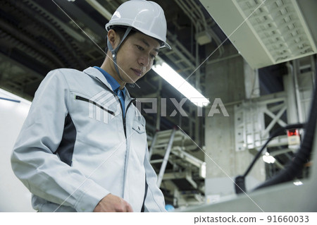 Male worker operating a machine in a factory 91660033
