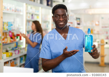 Pharmacist showing bottle with haircare product 91660143