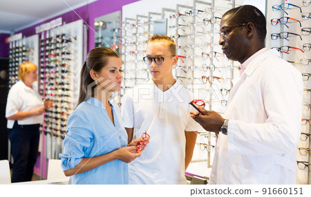 Young man and woman clients talking with ophthalmologist Young man and woman clients talking with ophthalmologist 91660151