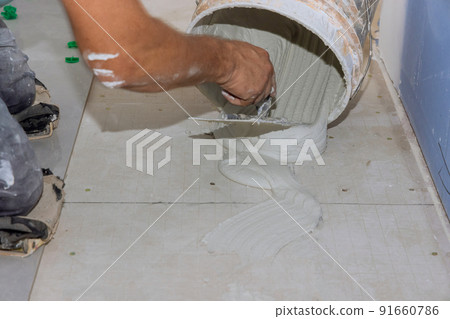 The adhesive on the bathroom floor is sprayed onto wet mortar before tiles are applied 91660786