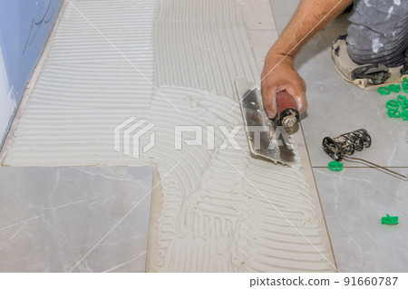 Using trowels to apply adhesive to concrete floors before tile-laying Using trowels to apply adhesive to concrete floors before tile-laying 91660787