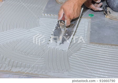 Bathroom renovation works with the adhesive on the bathroom floor is sprayed onto wet mortar before tiles are applied 91660790