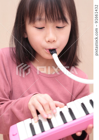 Girl playing keyboard harmonica 91661432
