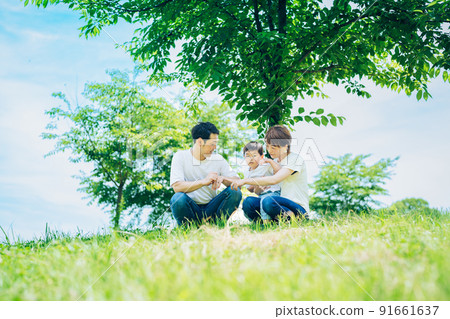 Parents and children sitting on a sunny green space Parents and children sitting on a sunny green space 91661637