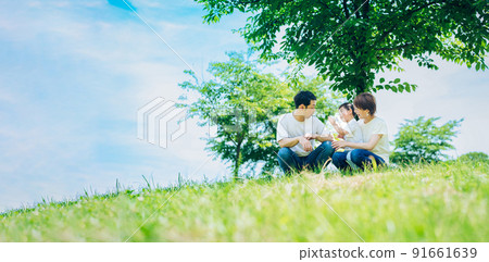 父母和孩子坐在陽光明媚的綠地上 91661639