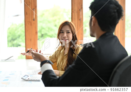 Beautiful millennial asian businesswoman having a nice conversation with male coworker 91662357