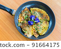 The omelet mix with climbing wattle, Acacia,  Blue Pea, Butterfly Pea, Thai vegetable herb on the frying pan. 91664175