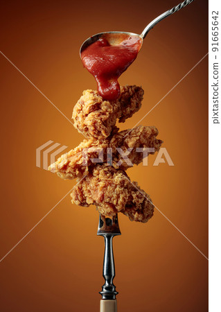 Fried chicken with ketchup on a fork. Fried chicken with ketchup on a fork. 91665642