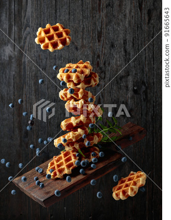 Waffles with fresh blueberries in motion. Waffles with fresh blueberries in motion. 91665643