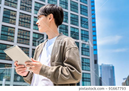 用平板電腦抬頭看著一個年輕的辦公室休閒商人 91667793