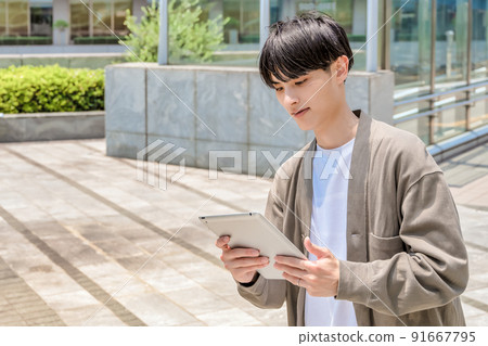 Looking up at a young office casual businessman with a tablet Looking up at a young office casual businessman with a tablet 91667795