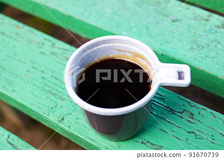 Plastic cup with coffee on a wooden bench 91670739