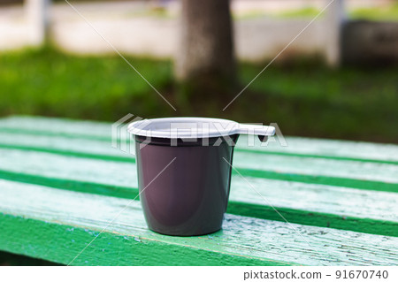 Plastic cup with coffee on a wooden bench 91670740