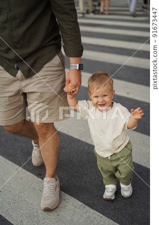 father and his cute baby son crossing road on zebra crossing holding hands father and his cute baby son crossing road on zebra crossing holding hands 91673447