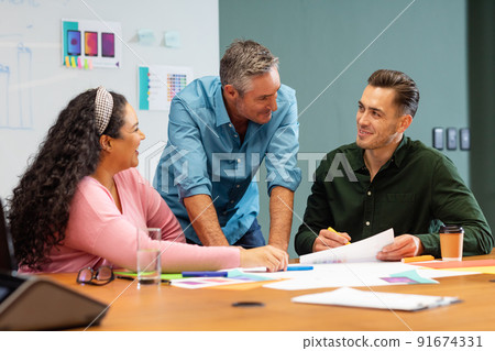 Businessman explaining business strategy to multiracial colleagues in meeting at creative office 91674331