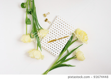 A bouquet of spring yellow tulips, a notebook on a white background and a golden pen. The concept of spring, women's and mother's day, birthday or blogging 91674448